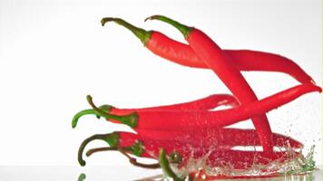 Super slow motion of chilli pepper falls on the water with spray. On a white background. Filmed on a high-speed camera at 1000 fps. High quality FullHD footage video