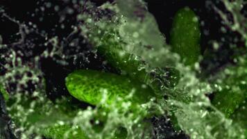 Super slow motion cucumbers fall on the water with splashes. On a black background. Filmed on a high-speed camera at 1000 fps. High quality FullHD footage video