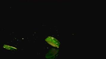 Super slow motion pieces of fresh cucumber fall on the water with splashes. On a black background.Filmed on a high-speed camera at 1000 fps. High quality FullHD footage video