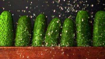 Super slow motion on fresh cucumbers in a row drops water. On a black background. Filmed on a high-speed camera at 1000 fps.High quality FullHD footage video