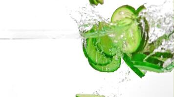 Super slow motion pieces of fresh cucumbers fall into the water with splashes. On a white background.Filmed on a high-speed camera at 1000 fps. High quality FullHD footage video