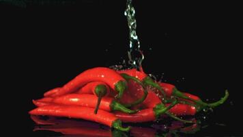 Super slow motion on a bunch of sharp chili peppers drops water. On a black background. Filmed on a high-speed camera at 1000 fps. High quality FullHD footage video