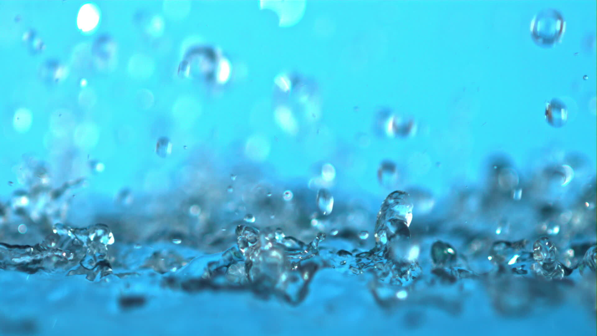 Super slow motion splashes water on a blue background. Filmed on a high