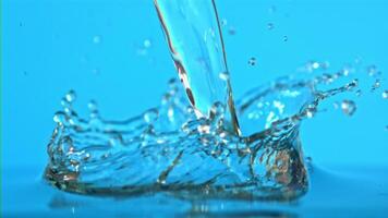 super lent mouvement l'eau chutes sur le table sur une bleu Contexte. filmé sur une haute vitesse caméra à 1000 ips. haute qualité Full HD métrage video