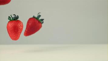 súper lento movimiento delicioso fresas caídas dentro el Leche con salpicaduras en un blanco fondo.filmado en un alta velocidad cámara a 1000 fps video