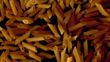 Super slow motion dry penne paste. On a black background. Filmed on a high-speed camera at 1000 fps. High quality FullHD footage video