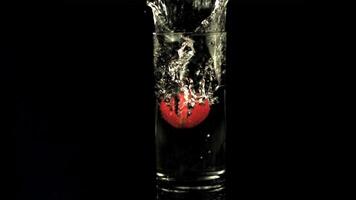 súper lento movimiento en un vaso de agua gotas fresas con salpicaduras en un negro fondo.filmado en un alta velocidad cámara a 1000 fps video