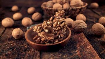 Super slow motion plate with walnuts falls on the table. On a wooden background.Filmed on a high-speed camera at 1000 fps. High quality FullHD footage video