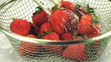 Super slow motion on the strawberries in the colander drops water. On a white background.Filmed on a high-speed camera at 1000 fps video