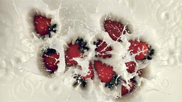 Super slow motion a lot of strawberries fall into the milk with splashes. Macro background. Top view. Filmed on a high-speed camera at 1000 fps video