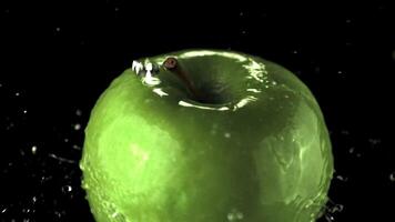 Super slow motion water droplets fall on the rotating apple. On a black background. Filmed on a high-speed camera at 1000 fps. High quality FullHD footage video