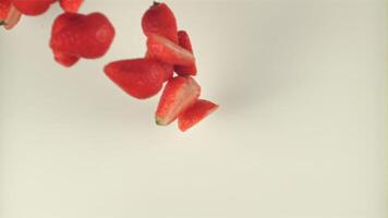 Super slow motion pieces of strawberries fall into the milk. On a white background. Filmed on a high-speed camera at 1000 fps video