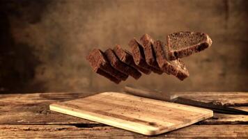 Super schleppend Bewegung auf das Schneiden Tafel fallen Stücke von Brot. gegen ein dunkel Hintergrund. gefilmt auf ein schnelle Geschwindigkeit Kamera beim 1000 fps. video