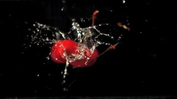 Super slow motion ripe cherry falls into the water with splashes. On a black background.Filmed on a high-speed camera at 1000 fps. video