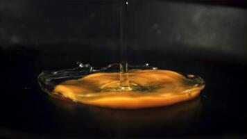 super lento movimento crudo uovo cascate su un' caldo frittura padella. su un' nero sfondo. girato su un' alta velocità telecamera a 1000 fps. video