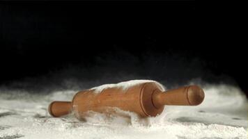 Super slow motion wooden rolling pin falls on the table with flour. Filmed on a high-speed camera at 1000 fps.On a black background. High quality FullHD footage video