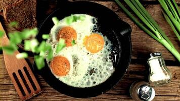 Super slow motion chopped green onions drops into the pan with fried eggs. On a wooden background.Filmed on a high-speed camera at 1000 fps. video