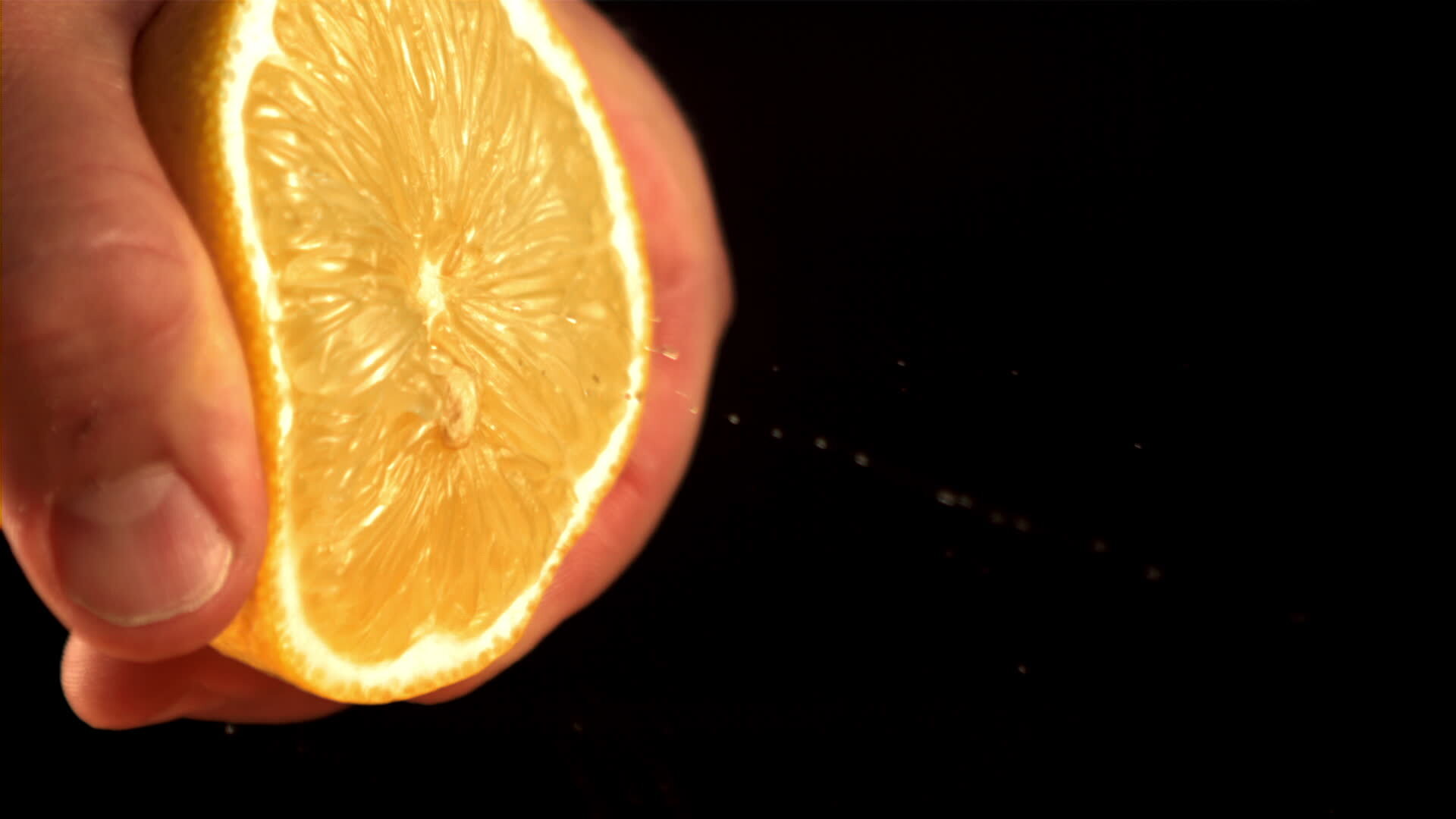 Super slow motion the man's hand squeezes the juice out of the fresh