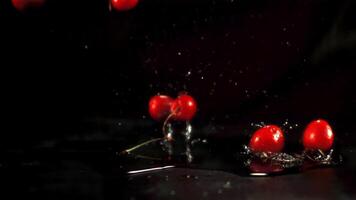 súper lento movimiento Cereza caídas en el mesa con agua rociar. en un negro antecedentes. filmado en un alta velocidad cámara a 1000 fps. alto calidad full HD imágenes video