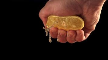 Super slow motion lemon juice squeezes out of fresh lemon the male hand. On a black background.Filmed on a high-speed camera at 1000 fps. video