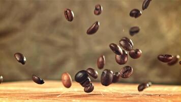 Coffee beans fall on a wooden board. Filmed on a high-speed camera at 1000 fps. High quality FullHD footage video