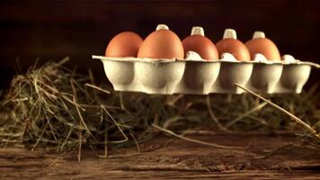 Super slow motion cardboard box with raw eggs falls on the table. On a wooden background. Filmed on a high-speed camera at 1000 fps.High quality FullHD footage video