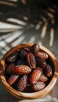 AI generated Dates in wooden bowl on gray marble surface with tree shadow photo