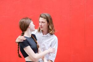 A couple is enjoying a summer vacation in the red wall background, happily showing their love to each other. photo