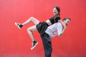 un Pareja es disfrutando un verano vacaciones en el rojo pared fondo, felizmente demostración su amor a cada otro. foto