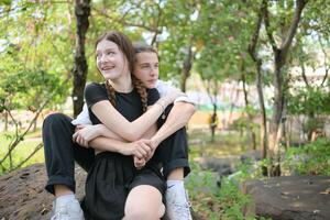 A couple is enjoying a summer vacation in the park, happily showing their love to each other. photo