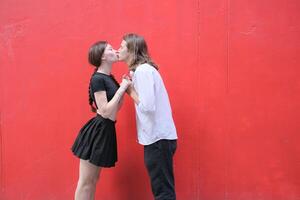 A couple is enjoying a summer vacation in the red wall background, happily showing their love to each other. photo