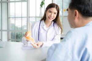 In the hospital office, A medical explains about the foot bones and their treatment to a patient photo