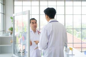 A medical professor and a medical student discuss a case study involving disease therapy for a hospital patient. photo