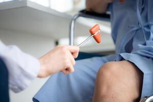 un médico usos un reflejo martillo a evaluar un del paciente rodilla articulación foto