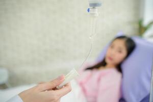 Female doctor with IV equipment will give IV fluids and examine patients lying in hospital beds photo