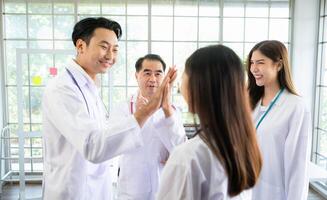 A delighted doctor team enjoying achievement in a hospital setting with high five. photo