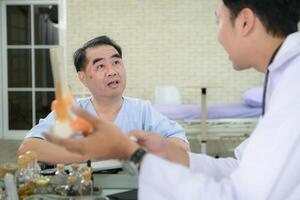 In the hospital office, A medical explains about the foot bones and their treatment to a patient photo