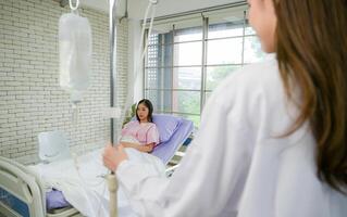 Female doctor with IV equipment will give IV fluids and examine patients lying in hospital beds photo