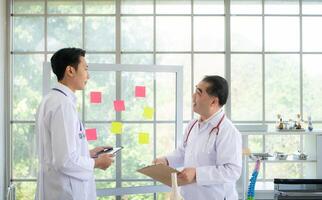 A medical professor and a medical student discuss a case study involving disease therapy for a hospital patient. photo