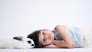 sonriente pequeño niña y con su amado mullido conejo, exhibiendo el belleza de amistad Entre humanos y animales foto