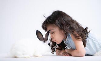 un pequeño niña Besos su amado mullido conejo, el belleza de amistad Entre humanos y animales foto