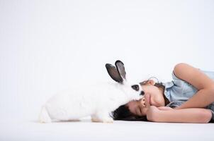 sonriente pequeño niña y con su amado mullido conejo, exhibiendo el belleza de amistad Entre humanos y animales foto