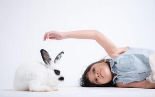 sonriente pequeño niña y con su amado mullido conejo, exhibiendo el belleza de amistad Entre humanos y animales foto