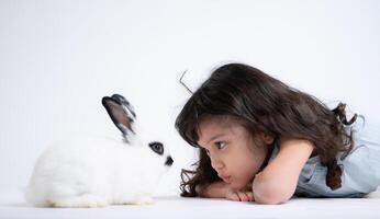 un pequeño niña Besos su amado mullido conejo, el belleza de amistad Entre humanos y animales foto