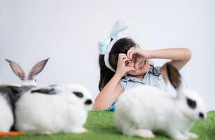 sonriente pequeño niña y con su amado mullido conejo, exhibiendo el belleza de amistad Entre humanos y animales foto