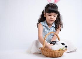 sonriente pequeño niña y con su amado mullido conejo, exhibiendo el belleza de amistad Entre humanos y animales foto