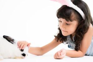 sonriente pequeño niña y con su amado mullido conejo, exhibiendo el belleza de amistad Entre humanos y animales foto