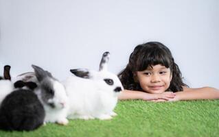 sonriente pequeño niña y con su amado mullido conejo, exhibiendo el belleza de amistad Entre humanos y animales foto