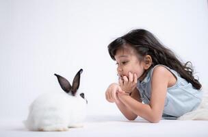 sonriente pequeño niña y con su amado conejo, exhibiendo el belleza de amistad Entre humanos y animales foto