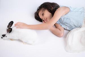 un pequeño niña Besos su amado mullido conejo, el belleza de amistad Entre humanos y animales foto
